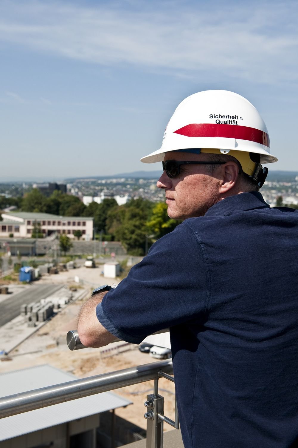Engenheiro de capacete observa um canteiro de obras do alto de um prédio